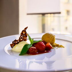 Angerichteter Dessertteller mit KPM-Logo im Hintergrund