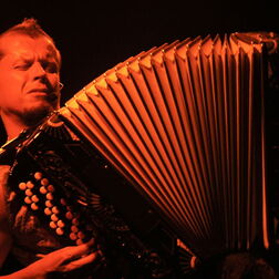 Mann mit Akkordion auf der Bühne in rotem Bühnenlicht