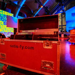 Eine rote Box in stimmungsvollem Raumlicht beim Aufbau einer Veranstaltung durch satis-fy
